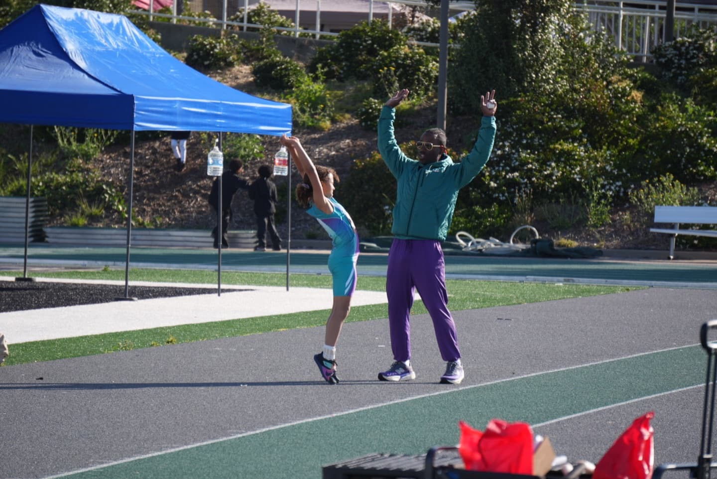 Coach Jason Jackson demonstrating a movement with a young track athlete.
